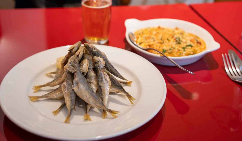 Carapauzinhos or baby horse mackel are lightly fried and served with tomato rice in Portugal