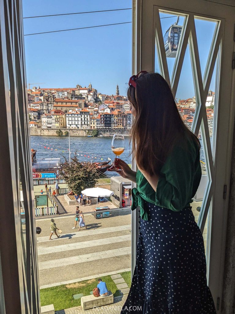 Daniela holding a glass of port wine in the tasting room at Ramos Pinto, looking at Porto from Vila Nova de Gaia