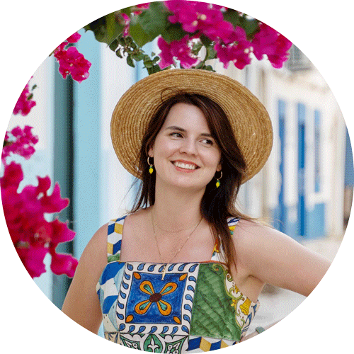 Headshot of Daniela Sunde-Brown in a tiled dress with a straw hat on